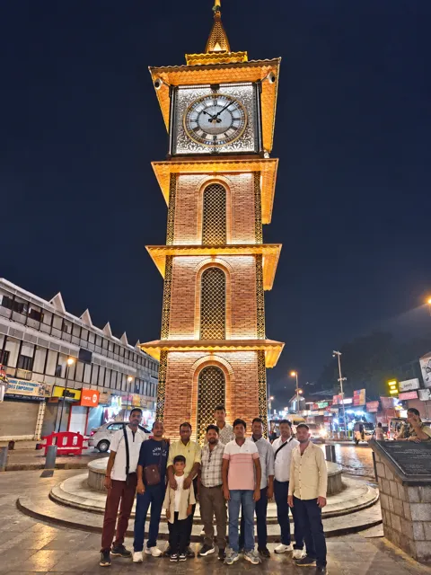 Travellers beside an illuminated clock tower