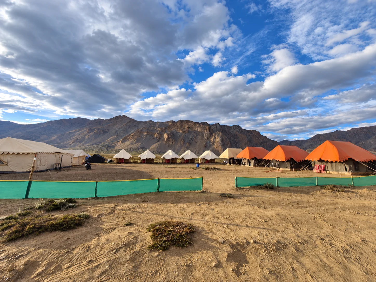 Mountain campsite beneath an expansive blue and cloudy sky